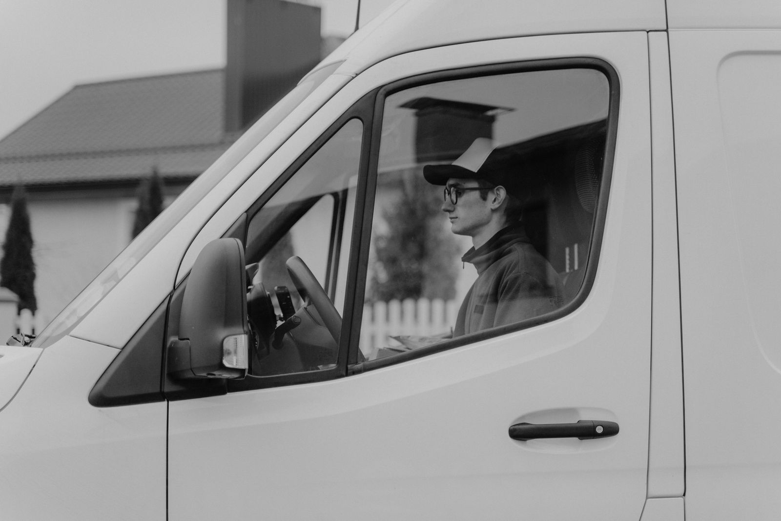 Delivery driver seen through the driver's side window of a white cargo van