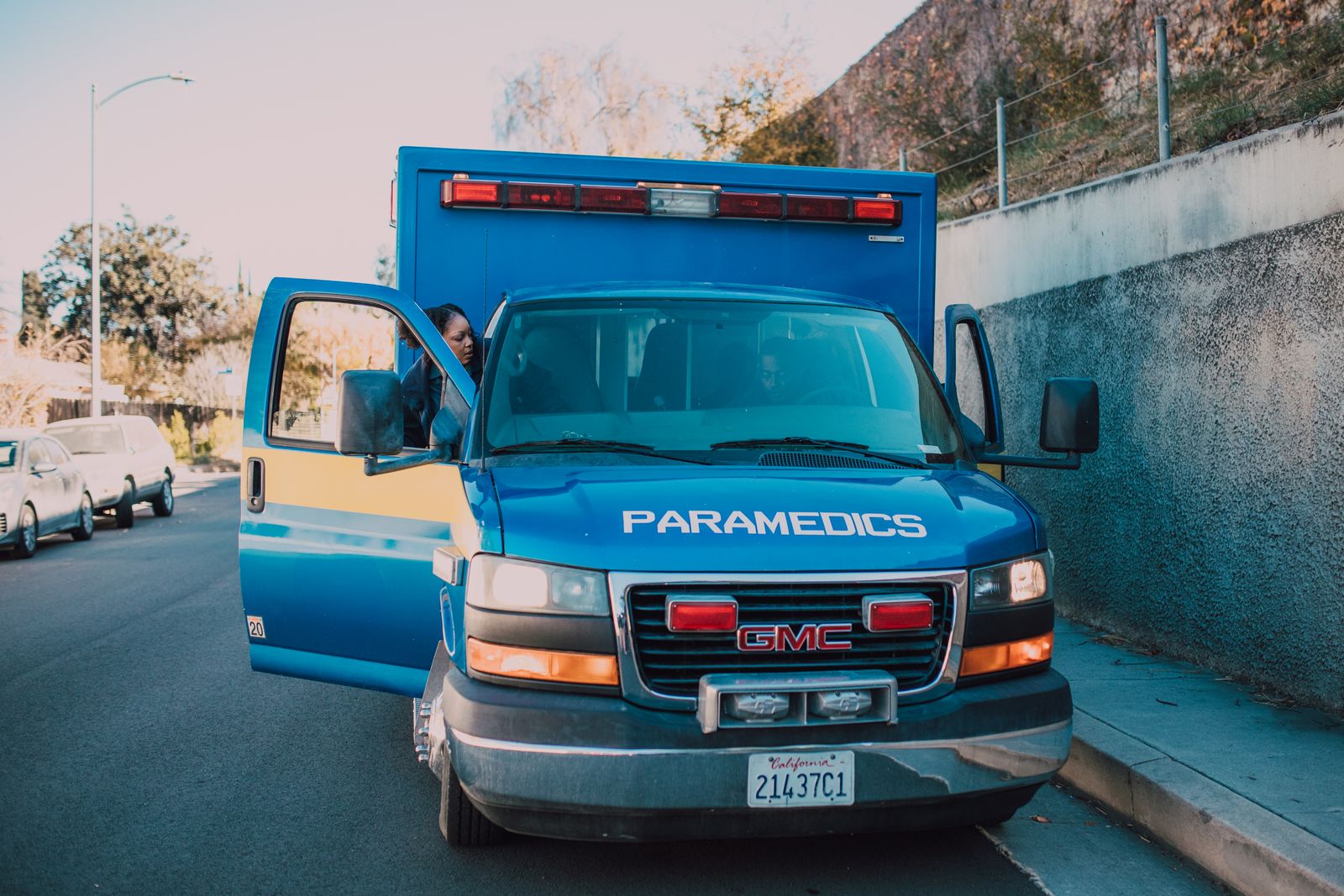 Ambulance marked PARAMEDICS parked on a street with the driver door open