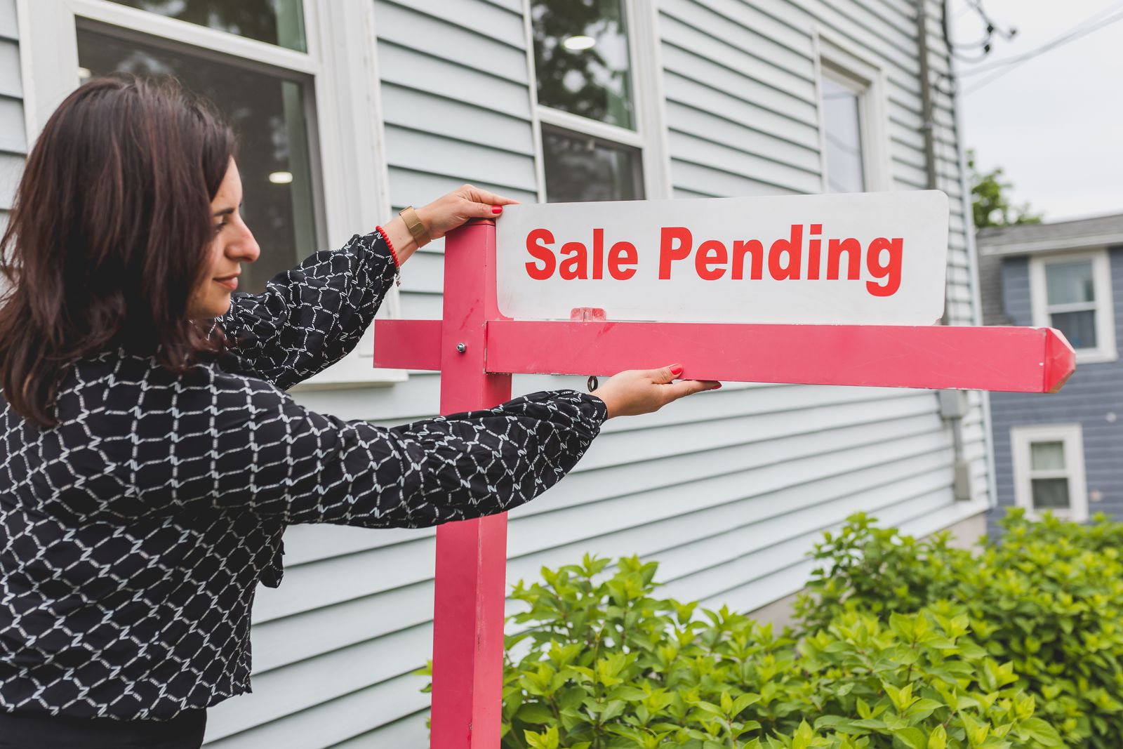 Real estate agent placing a Sale Pending sign in front of a house