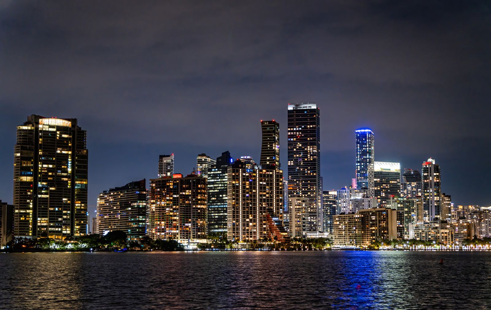Miami downtown skyline at night, illuminated high-rise towers reflected in the waterfront