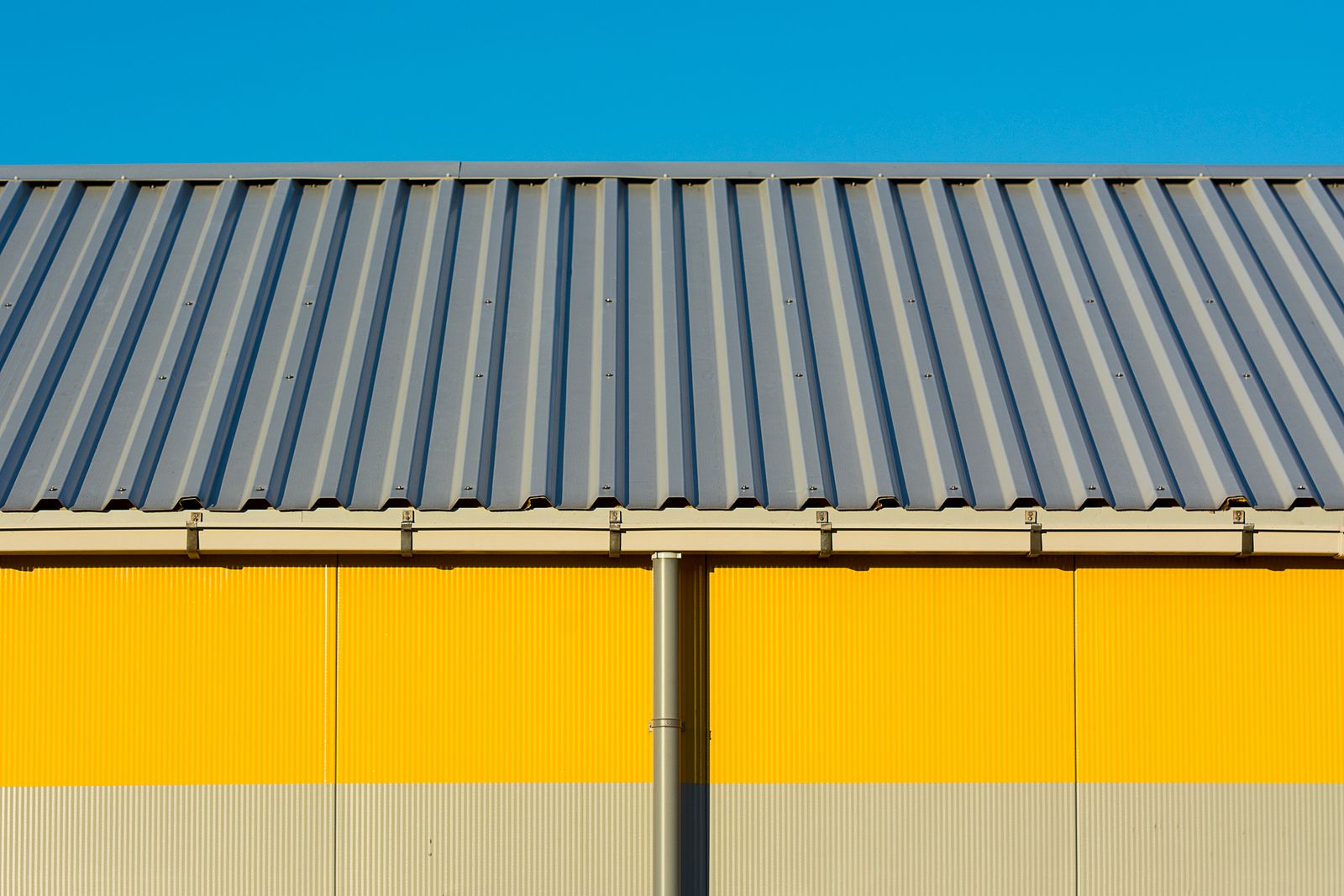Corrugated metal industrial building exterior against a clear blue sky