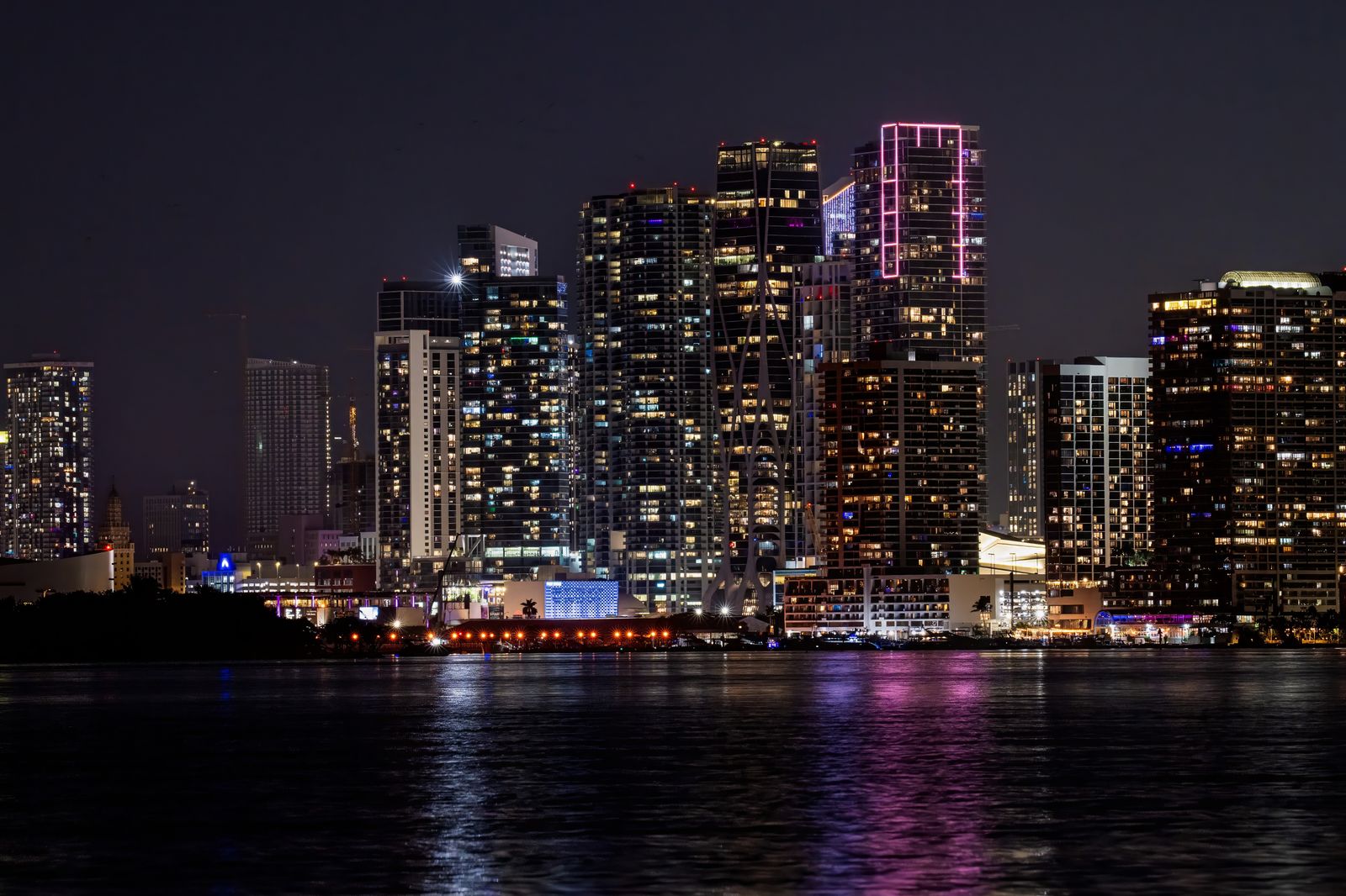Downtown Miami skyline at night with illuminated high-rise buildings reflected in the waterfront