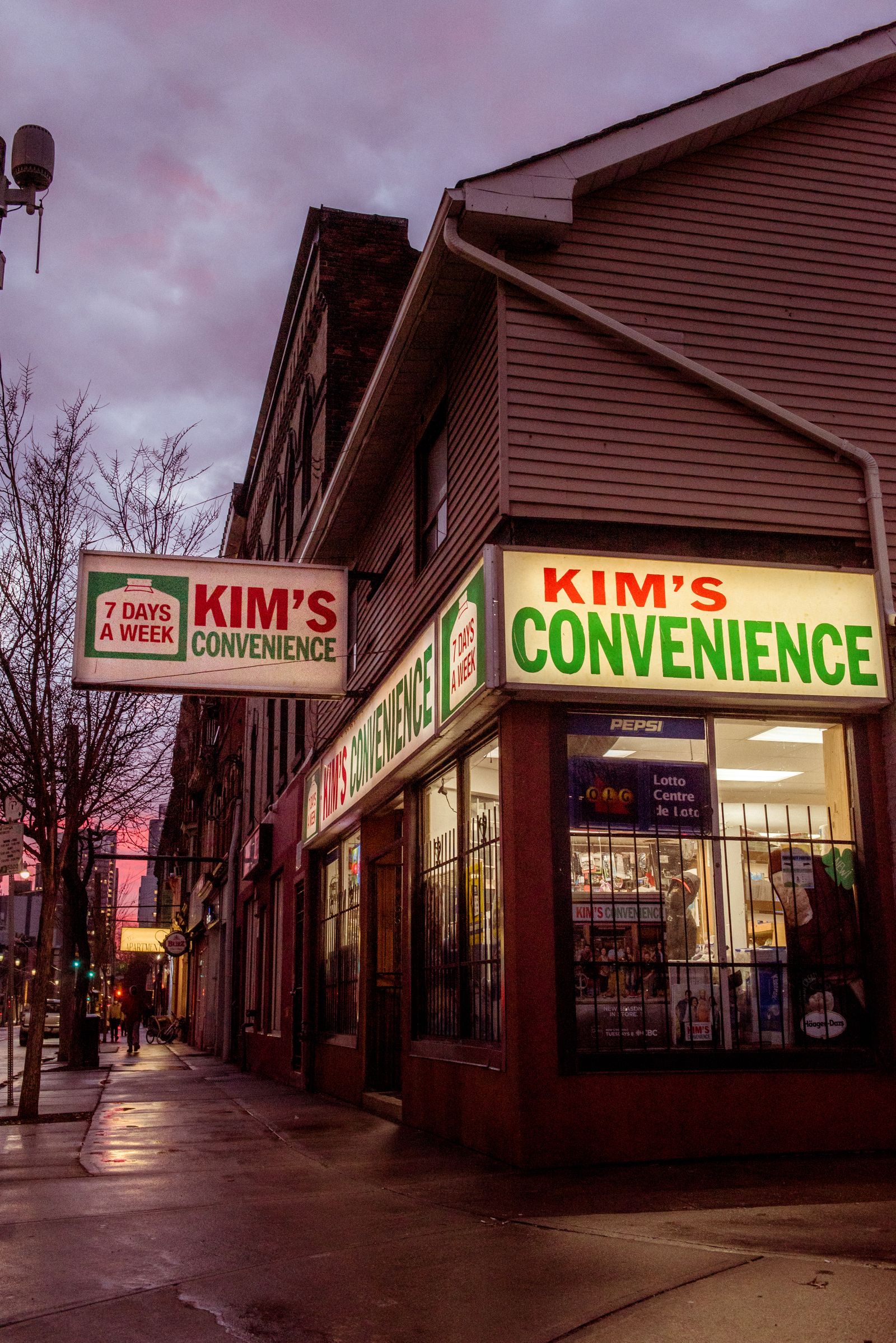 Illuminated storefront sign on a corner shop, photographed at dusk