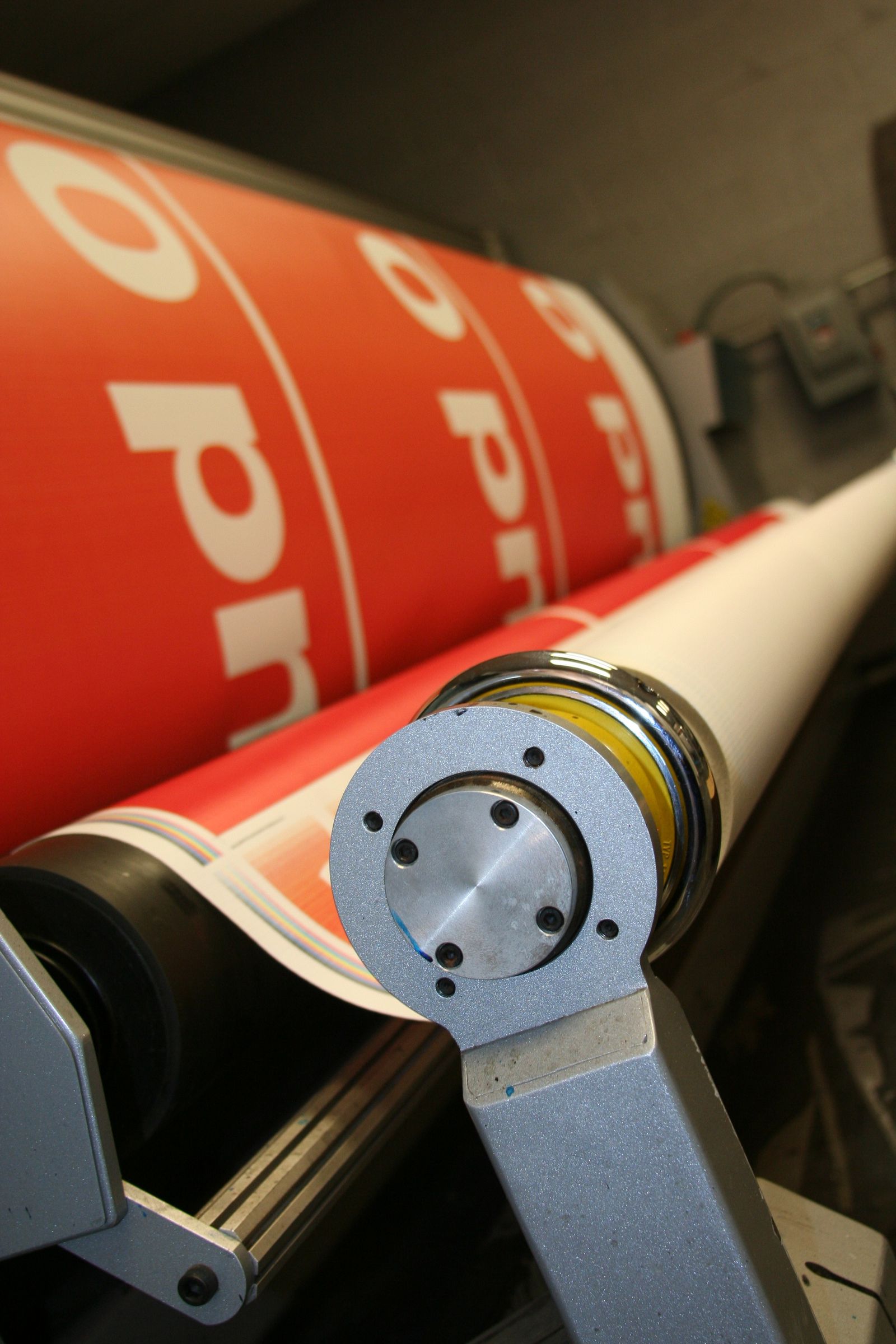 Close-up of an industrial large-format roll printer producing a red and white printed graphic